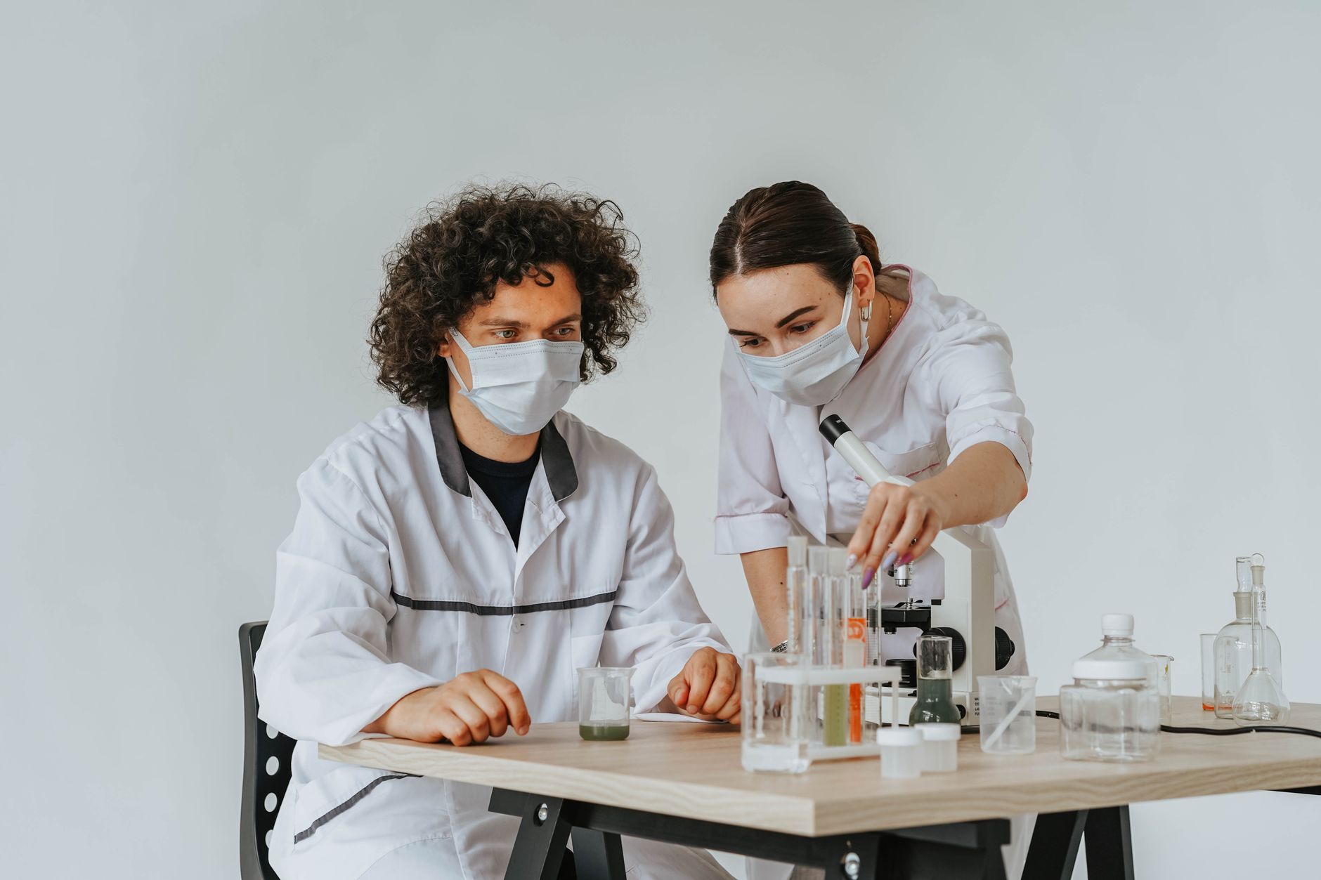 Two scientists working on experiments in a laboratory with microscopes and test tubes.