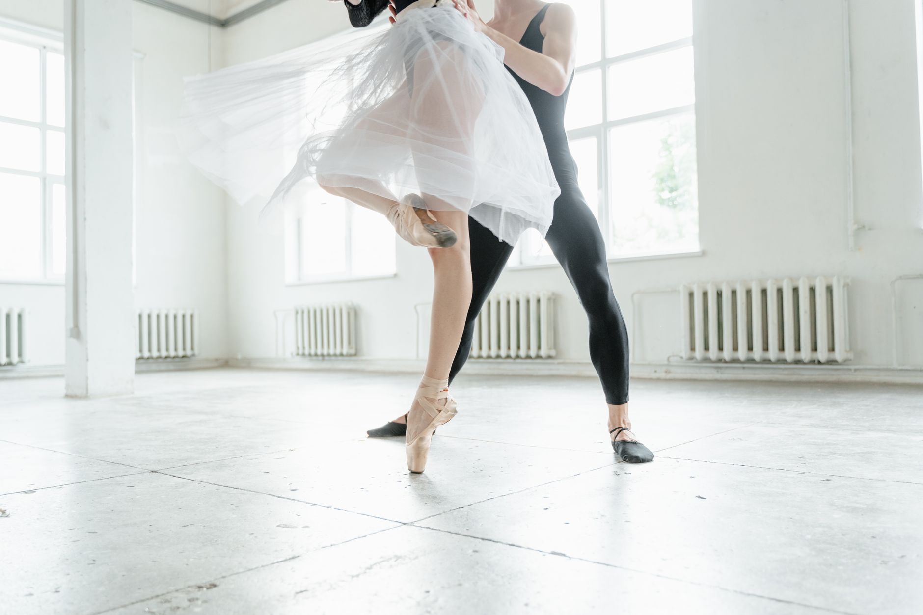 Ballet dancers practicing an elegant routine in a bright studio setting.