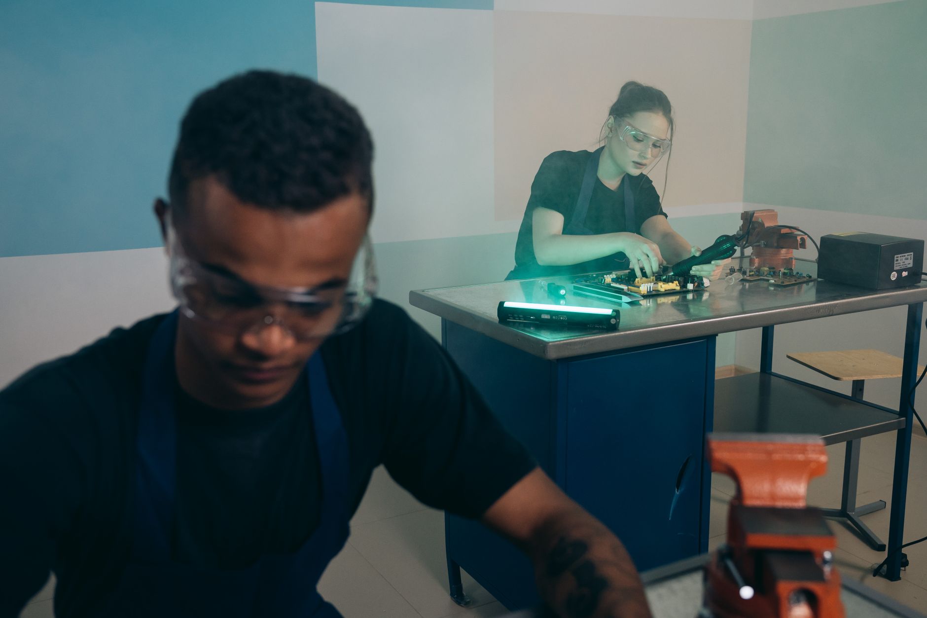 Two technicians focused on electronics repair work in a modern workshop setting.