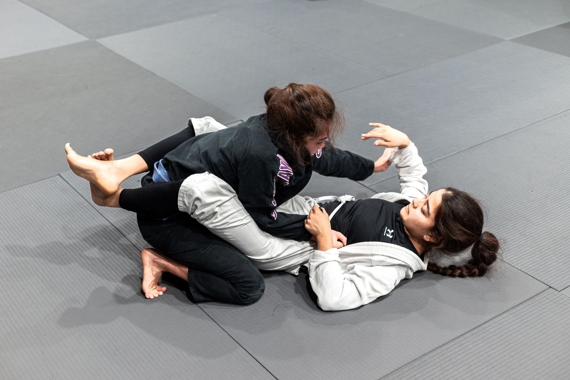 Two women engaging in jiu-jitsu practice on training mats in Buenos Aires, Argentina.