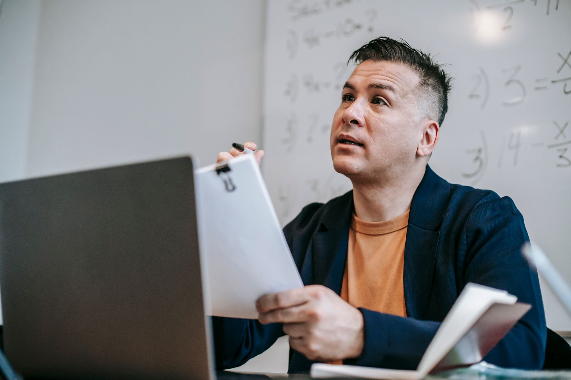 Educator discussing concepts during an online session, sitting at a desk with a laptop.