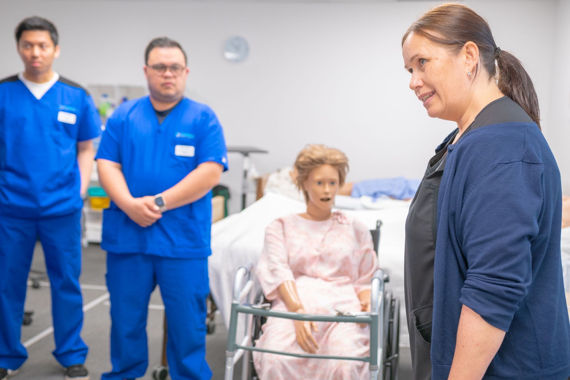 Nursing students and an instructor engage in a realistic clinical training using a medical mannequin.