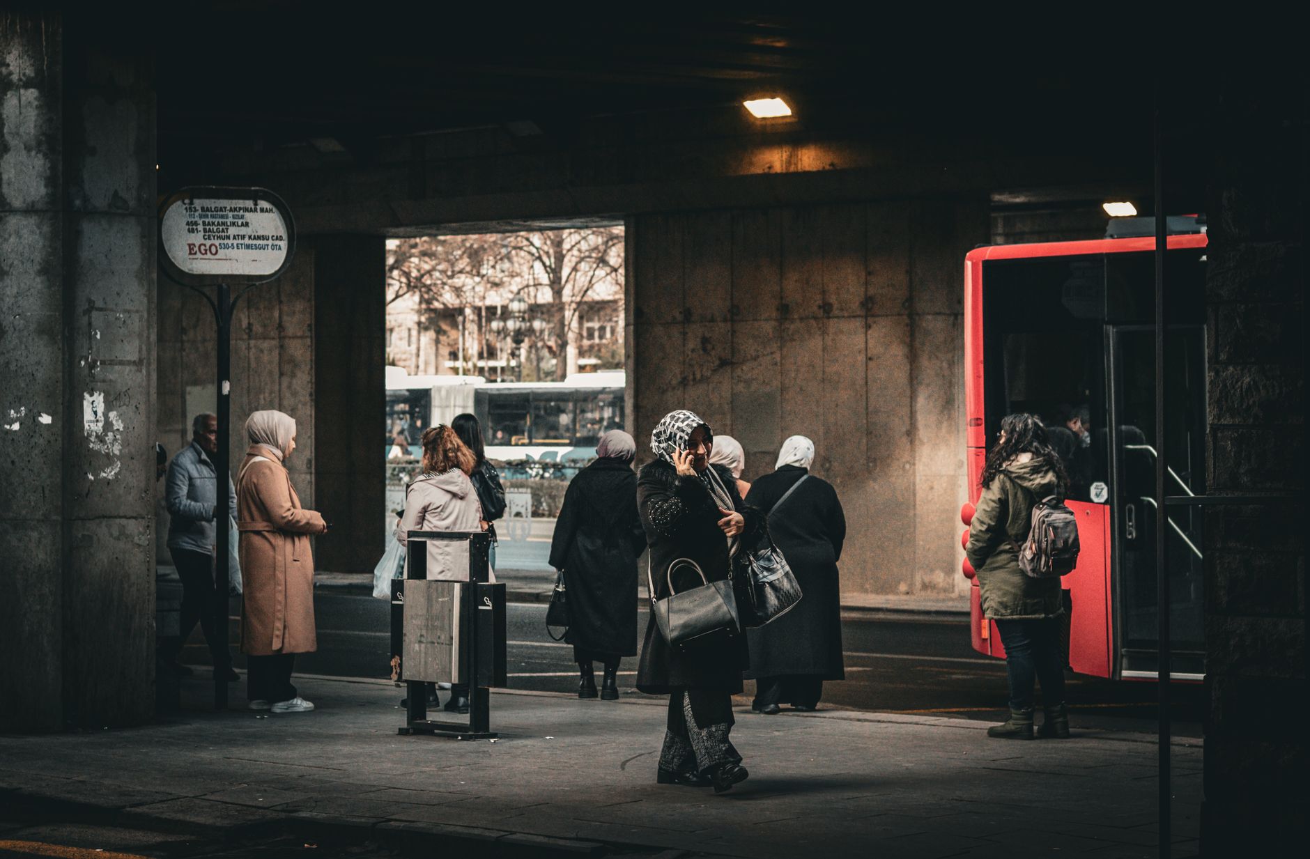 Commuters waiting at a bus stop in an urban setting, highlighting public transportation.