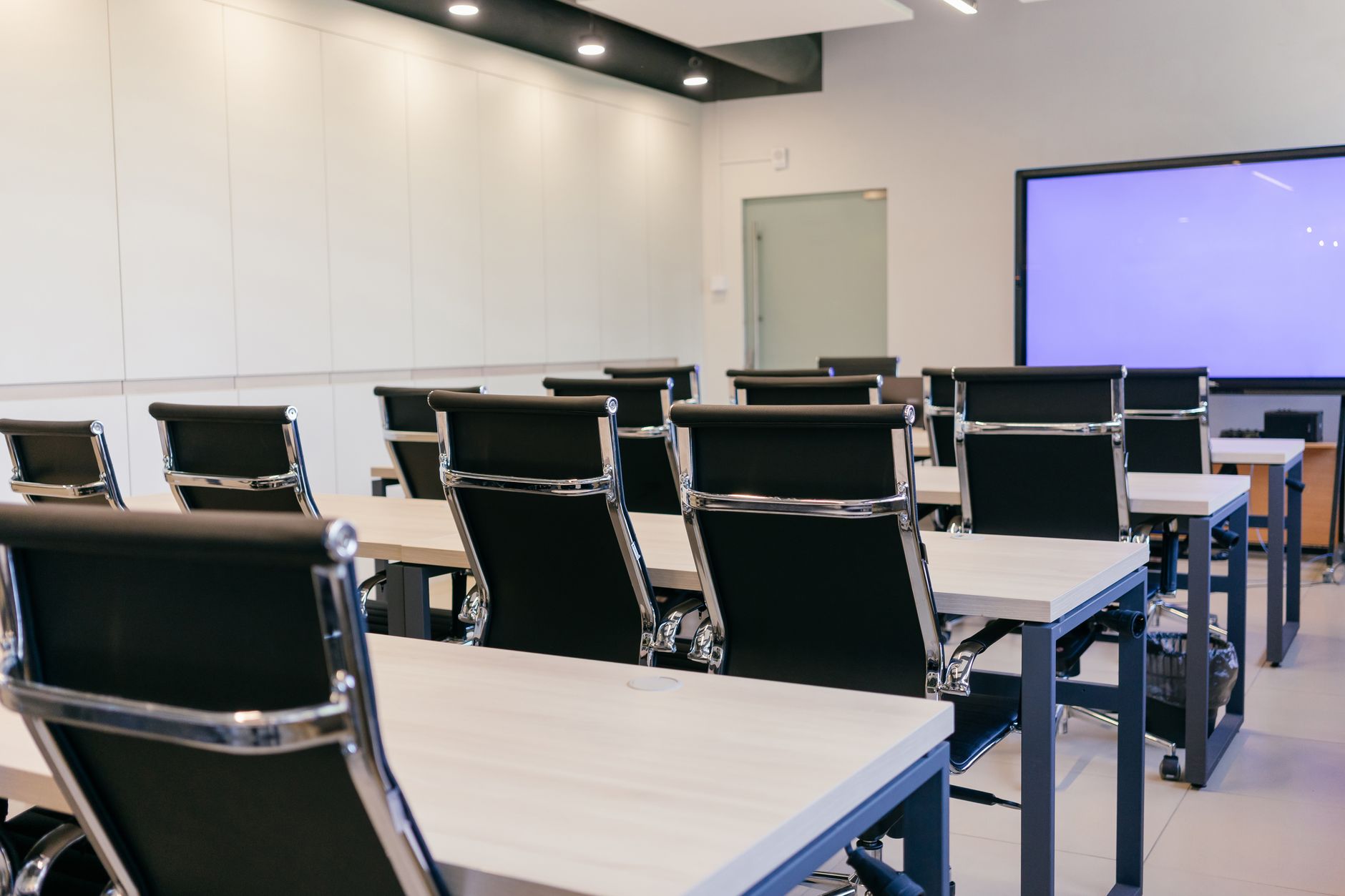 Spacious, modern conference room with black chairs and a projection screen.